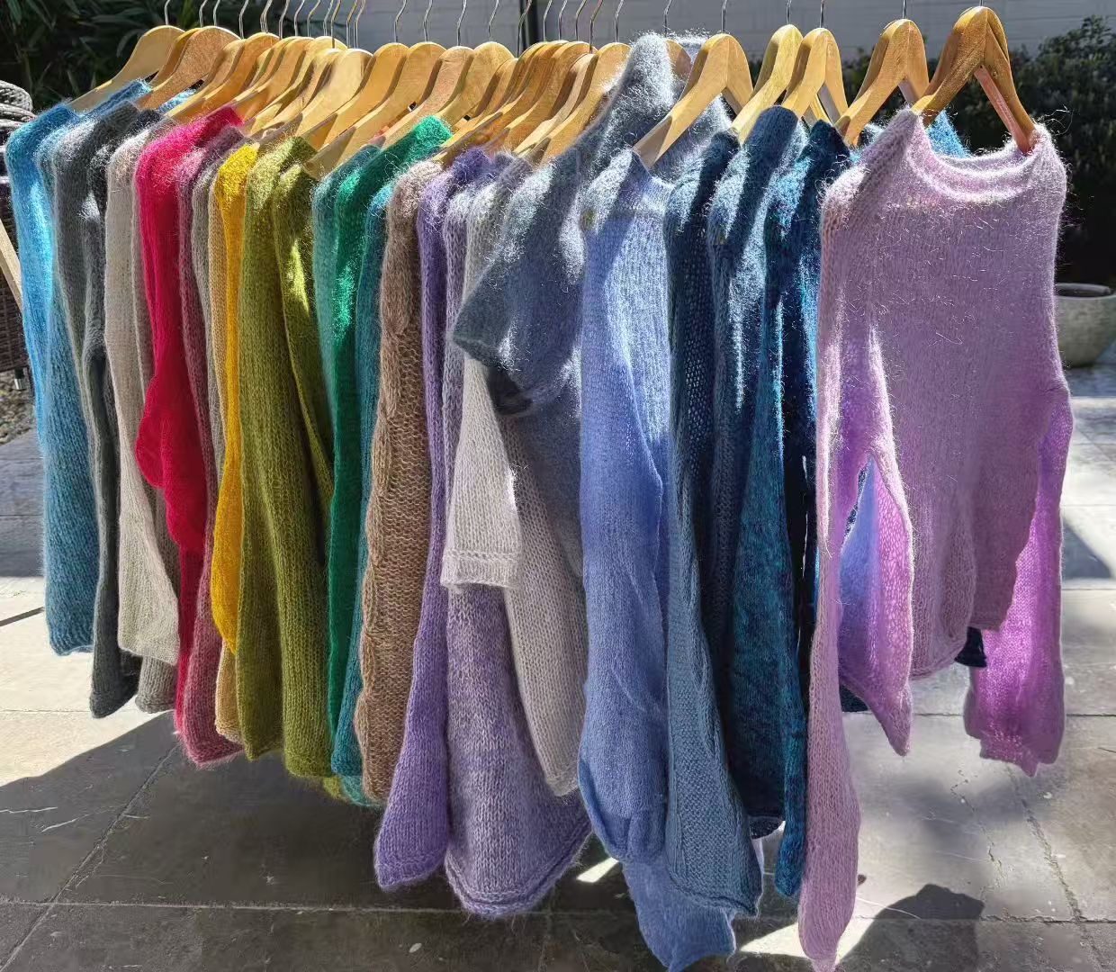 A rack of finished LAURA LANA mohair sweaters in the studio